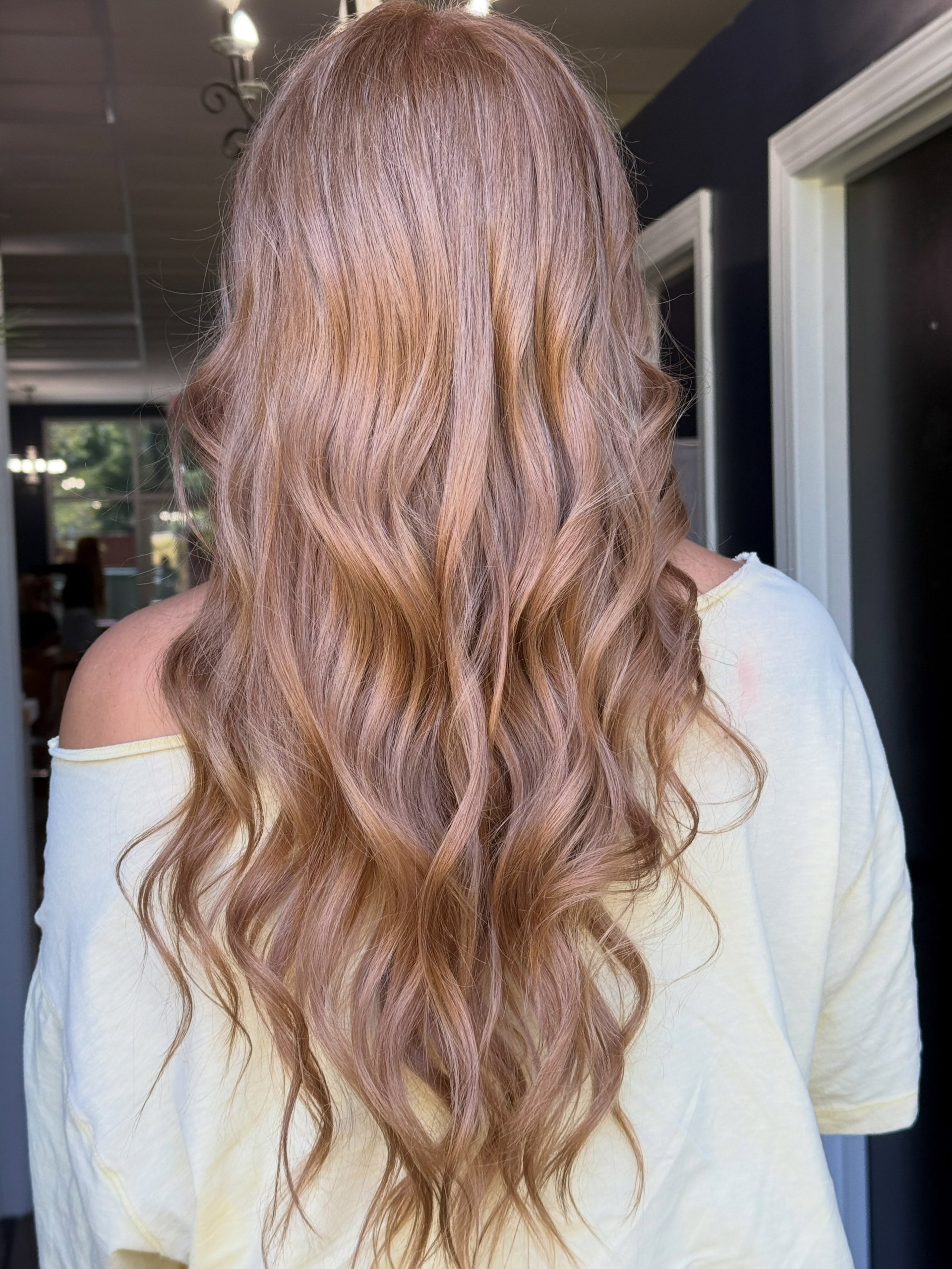Long strawberry-blonde hair styled in soft waves, viewed from behind.